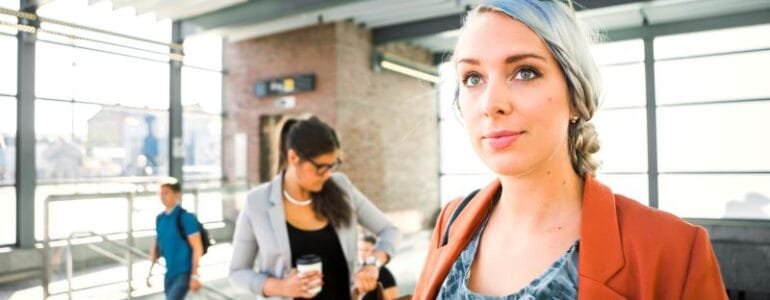 Businesswomen holding coffee cup while standing at railroad station