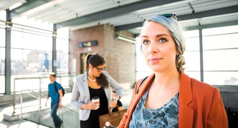 Businesswomen holding coffee cup while standing at railroad station